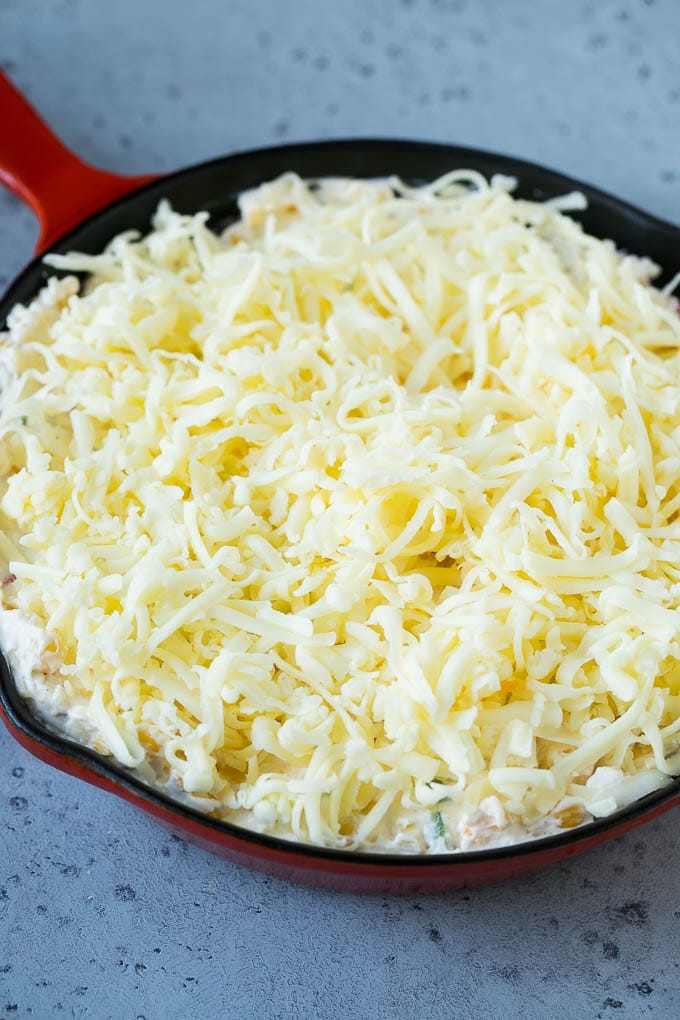 Corn Dip Recipe | Hot Cheese Dip | Bacon Dip #corn #dip #bacon #cheese #appetizer #snack #bajap A skillet of corn dip covered with shredded cheese.