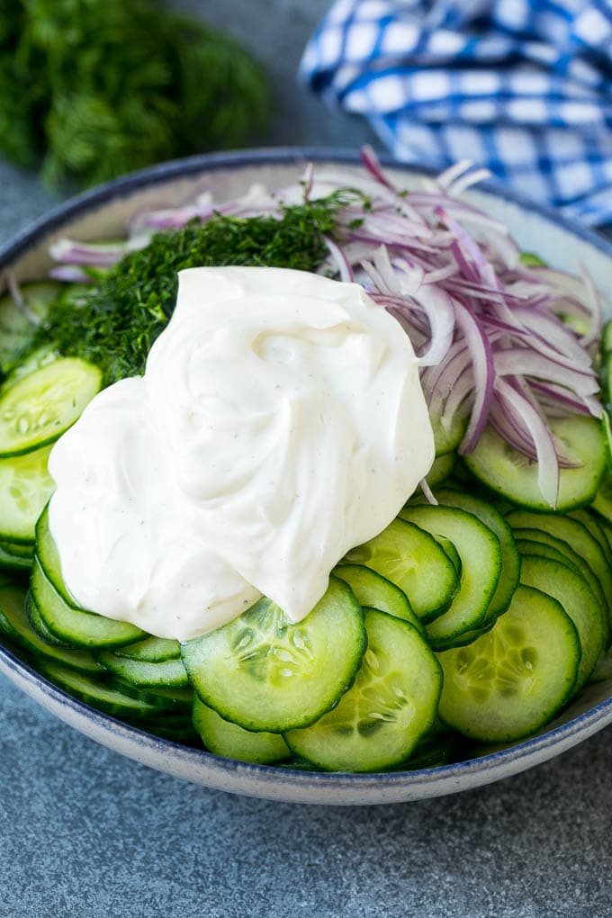 Creamy Cucumber Salad Recipe | German Cucumber Salad | Cucumber Salad #cucumber #salad #dinner #lunch #bajap #cucumbersalad Cucumbers, red onion and dill in a bowl topped with creamy dressing.