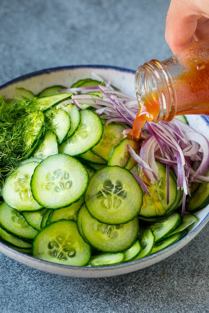 Cucumber Salad Recipe | Cucumber Dill Salad | Cucumber Recipe #cucumbers #salad #glutenfree #sidedish #bajap Dressing being poured over sliced vegetables and fresh dill.