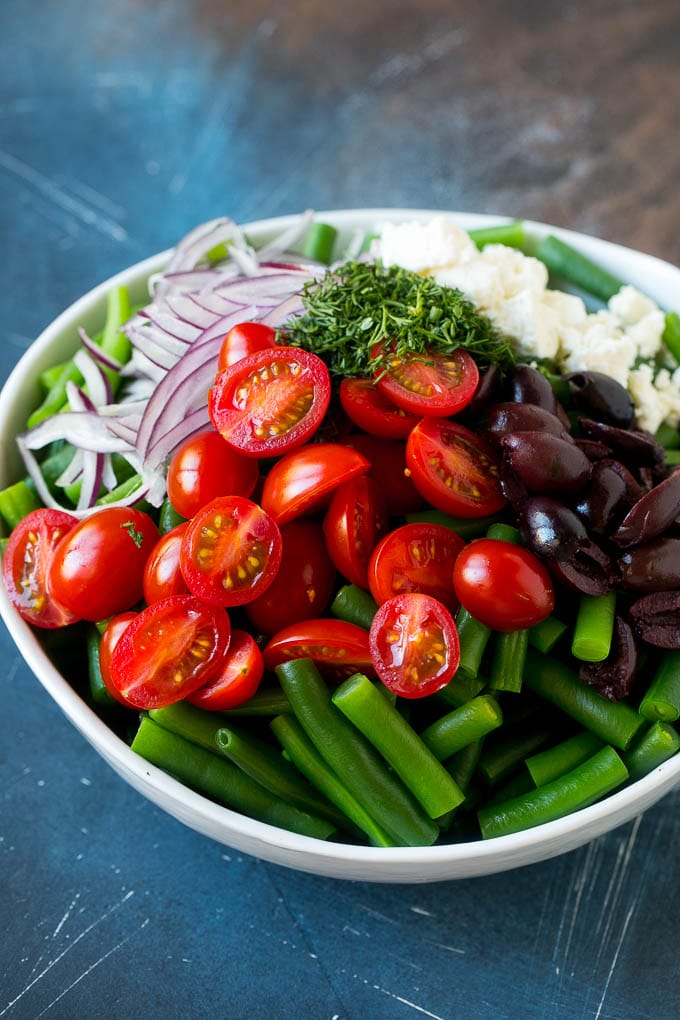 Green Bean Salad Recipe | String Bean Salad | Chopped Salad #greenbeans #tomatoes #olives #salad #cleaneating #lowcarb #glutenfree #bajap Vegetables like cherry tomatoes, red onion and olives in a bowl with feta cheese.