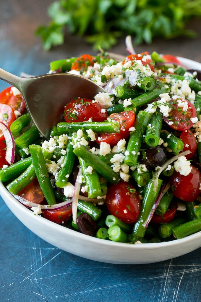 Green Bean Salad Recipe | String Bean Salad | Chopped Salad #greenbeans #tomatoes #olives #salad #cleaneating #lowcarb #glutenfree #bajap A serving spoon in a bowl of green bean salad.