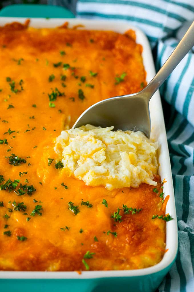 Hash Brown Casserole | Potato Casserole | Hash Brown Side Dish #potatoes #cheese #casserole #sidedish #bajap Hash brown casserole with potatoes, cheddar cheese, onions and sour cream, with a serving spoon in the dish.