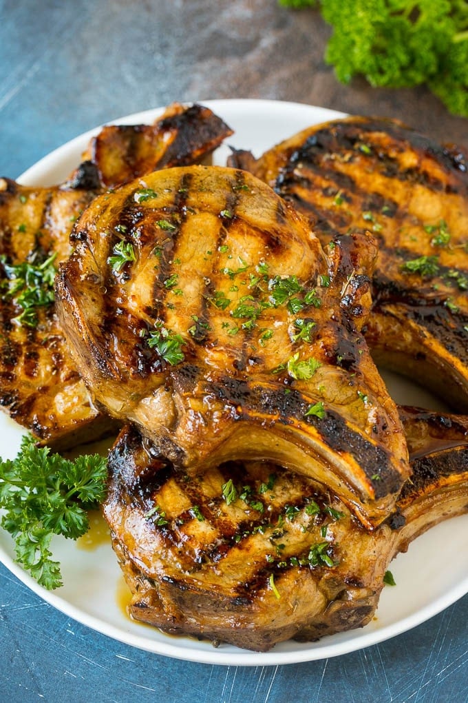 Pork Chop Marinade Recipe | Marinated Pork Chops | Grilled Pork Chops #pork #porkchops #grilling #dinner #bajap Pork chop marinade on grilled pork chops. The pork chops are on a serving plate garnished with parsley.