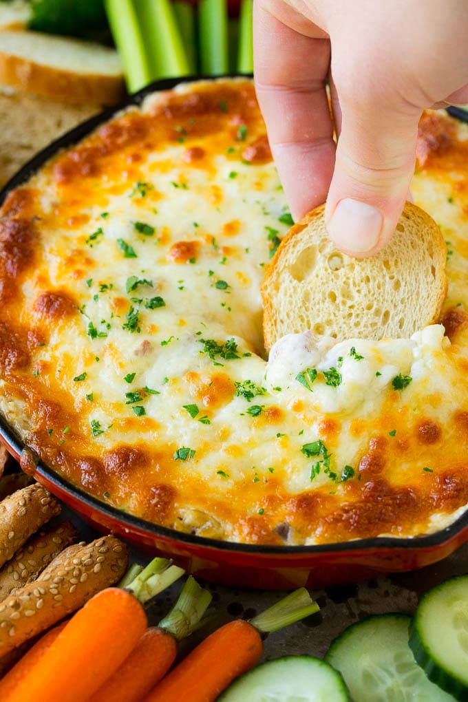 Reuben Dip Recipe | Corned Beef Dip | Cheese Dip #dip #cheese #cornedbeef #appetizer #lowcarb #keto #bajap A hand scooping out a serving of Reuben dip with baguette.