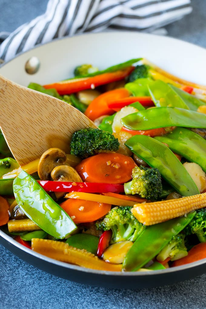 Vegetable Stir Fry Recipe | Veggie Stir Fry | Broccoli Stir Fry #vegetarian #vegetables #broccoli #dinner #bajap A spatula in a pan of veggie stir fry with carrots, snow peas and broccoli.