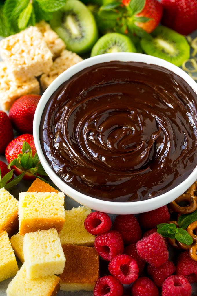 Chocolate Fondue Recipe | Chocolate Sauce | Chocolate Dip #chocolate #dessert #glutenfree #fondue #bajap A bowl of chocolate fondue surrounded by fruit, cake, rice krispy treats and pretzels.