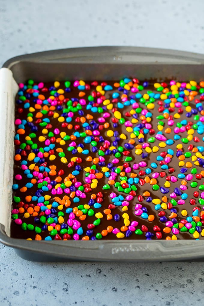 Cosmic Brownies Recipe | Cocoa Brownies | Frosted Brownies #brownies #chocolate #dessert #bajap #sprinkles A pan of cosmic brownies with rainbow sprinkles on top.