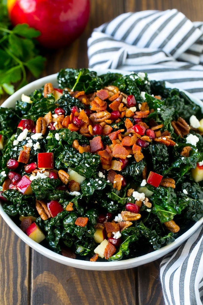 Apple Kale Salad Recipe | Kale Recipe | Fall Salad #kale #apples #bacon #salad #feta #dinner #lunch #bajap A bowl of tuscan kale salad garnished with cooked bacon.