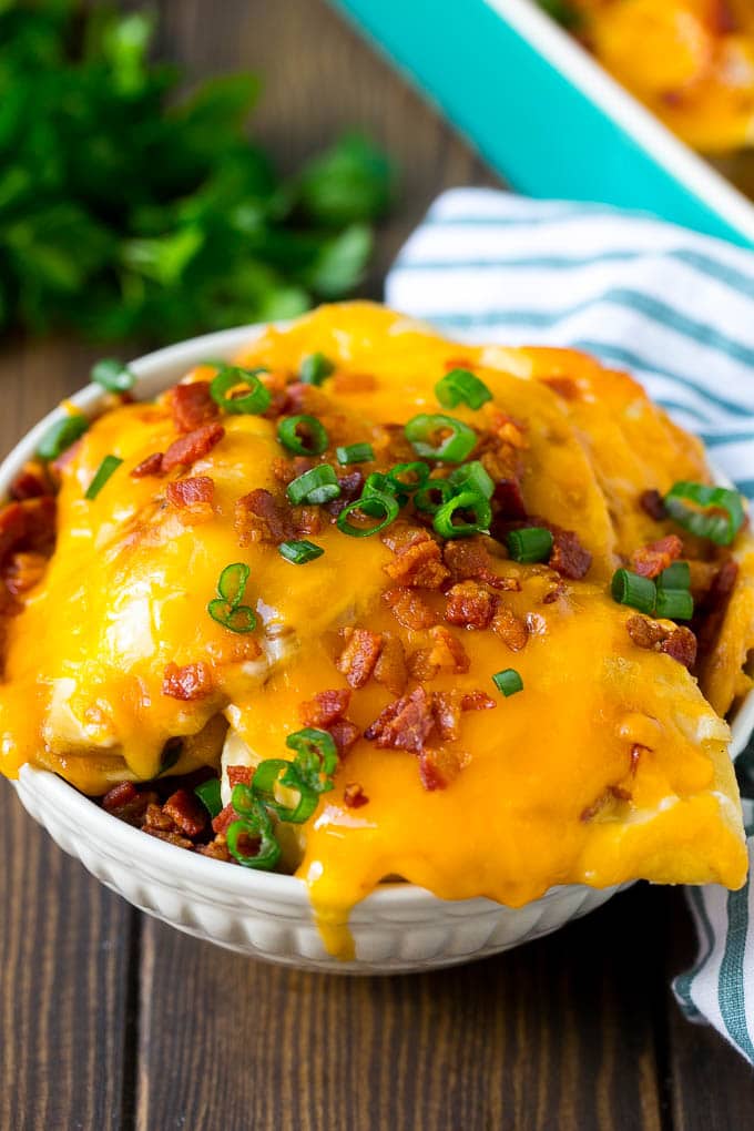 Pierogi Casserole Recipe | Potato Casserole #pierogis #casserole #bacon #cheddar #dinner #bajap A bowl of pierogi casserole topped with cheddar cheese and bacon.