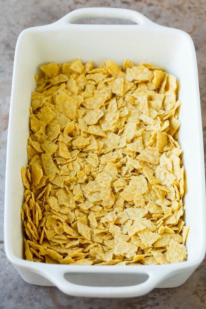 Taco Casserole Recipe | Mexican Casserole | Beef Casserole #casserole #tacos #beef #dinner #cheese #bajap Crushed tortilla chips in a casserole dish.