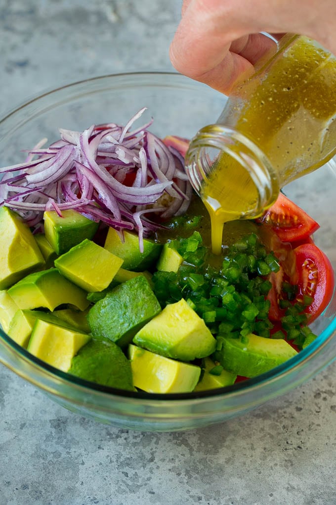 Tomato Avocado Salad Recipe | Avocado Salad | Tomato Salad #salad #tomato #avocado #glutenfree #cleaneating #dinner #bajap #healthy Dressing being poured over chopped veggies.