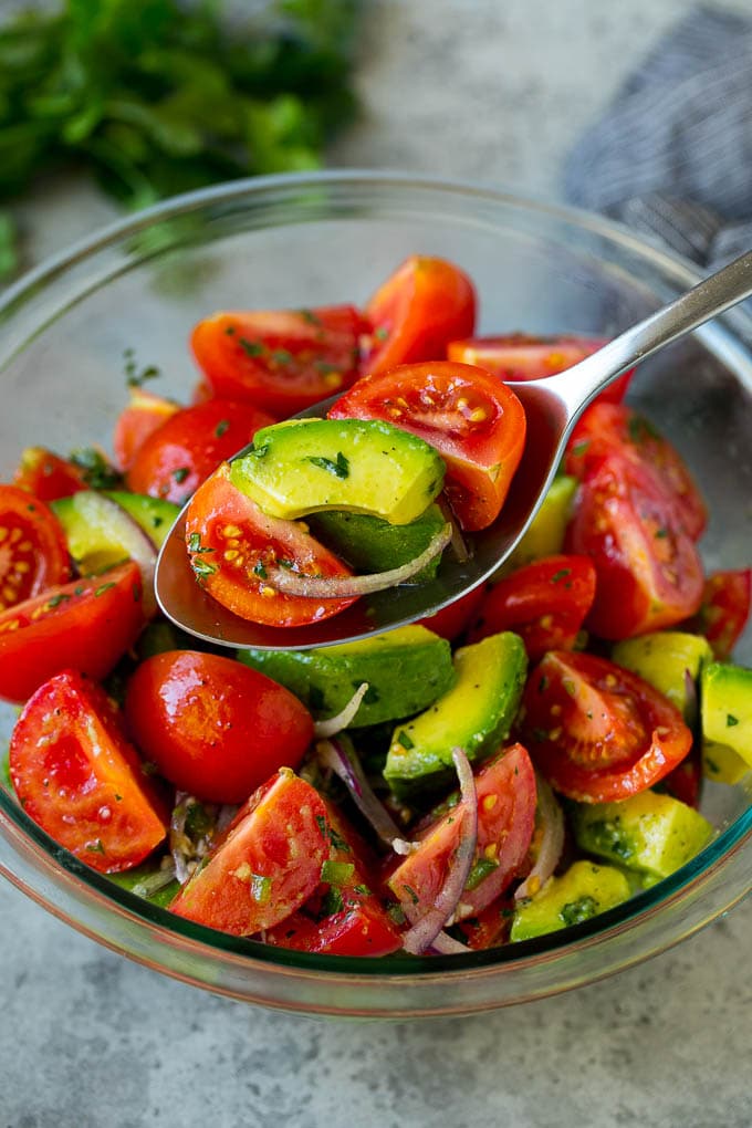 Tomato Avocado Salad Recipe | Avocado Salad | Tomato Salad #salad #tomato #avocado #glutenfree #cleaneating #dinner #bajap #healthy A serving spoon of veggies in a lime dressing.