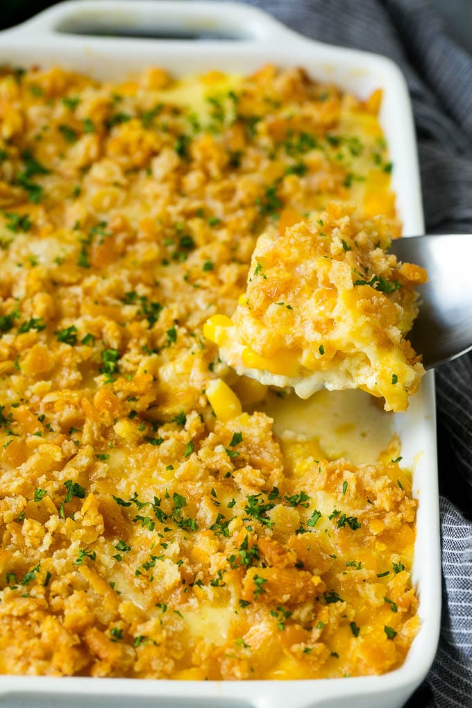 Scalloped Corn | Corn Casserole #corn #casserole #cheese #sidedish #dinner #bajap A serving spoon lifting out a portion of scalloped corn.