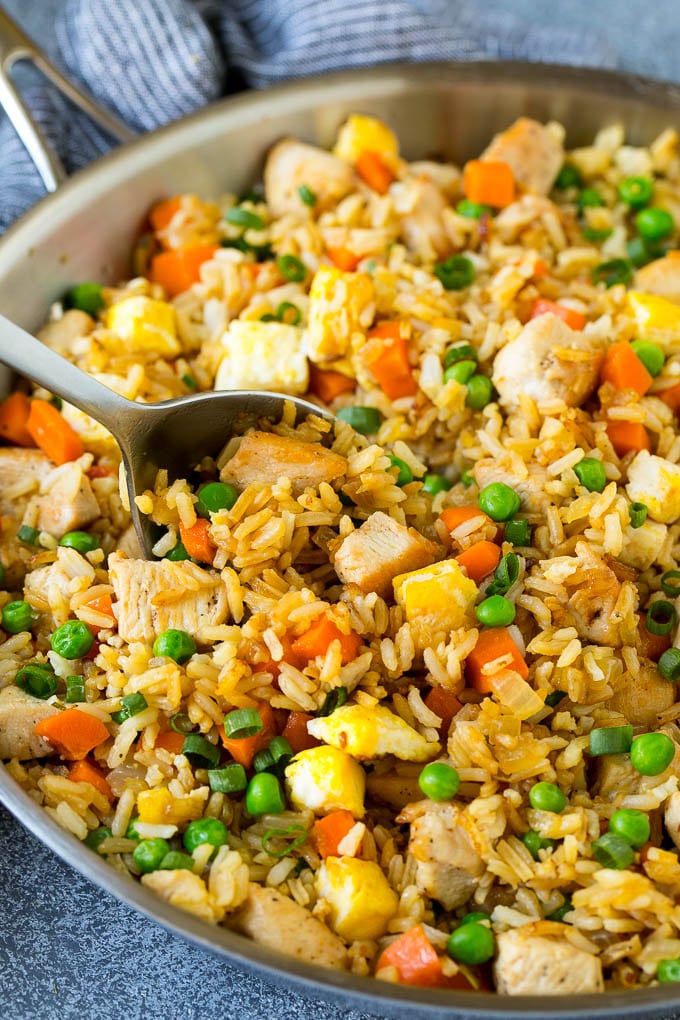 Chicken Fried Rice Recipe | Chinese Fried Rice #rice #chicken #peas #carrots #sidedish #dinner #bajap A serving spoon in a pan of chicken fried rice.
