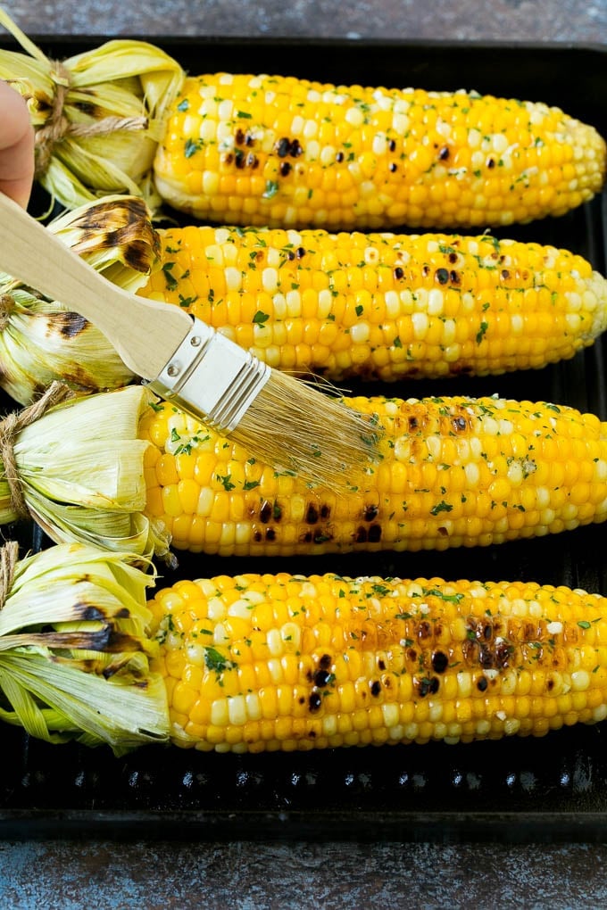 Grilled Corn on the Cob Recipe | Corn Recipe #corn #grilling #summer #sidedish #dinner #bajap Cobs being brushed with herb butter.