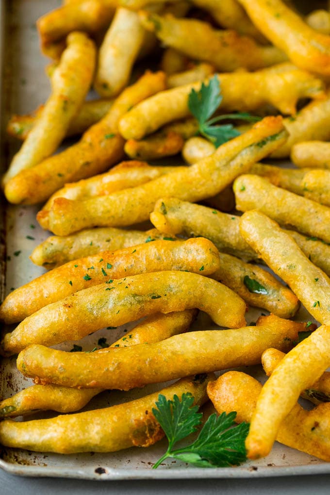 Fried Green Beans Recipe | Green Beans #greenbeans #appetizer #snack #bajap A sheet pan of fried green beans garnished with chopped parsley.
