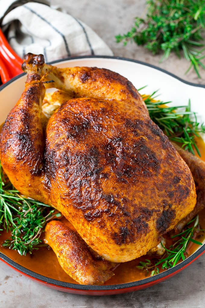 Rotisserie Chicken Recipe | Roasted Chicken #chicken #dinner #bajap #comfortfood A rotisserie chicken in a red skillet with sprigs of fresh herbs.