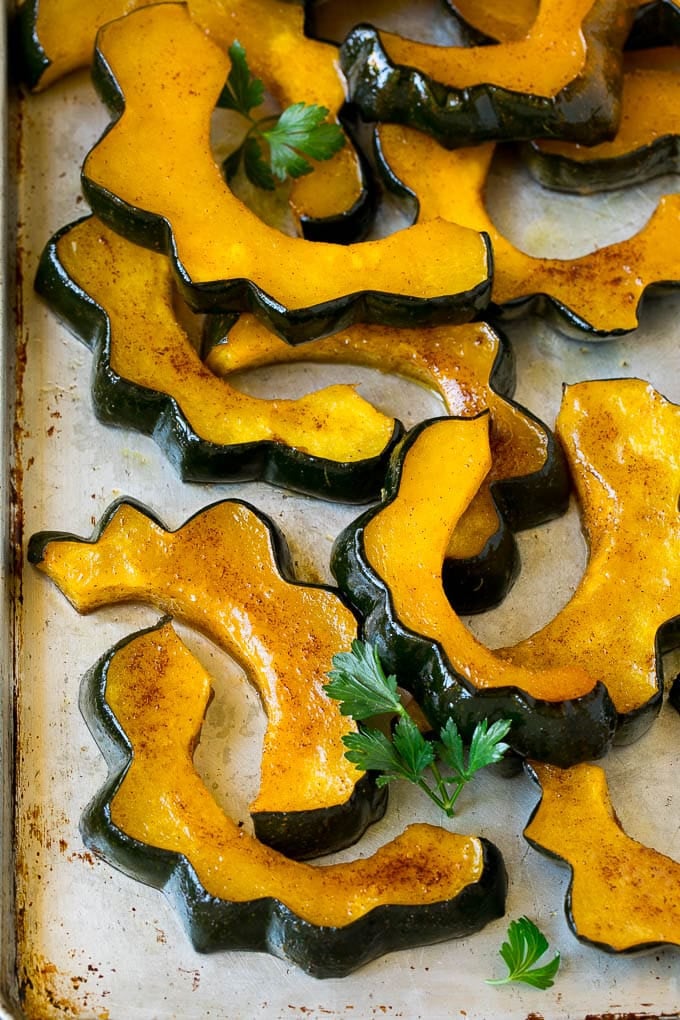Roasted Acorn Squash | Acorn Squash Recipe #squash #winter #sidedish #dinner #bajap Sliced of cinnamon roasted acorn squash on a sheet pan.