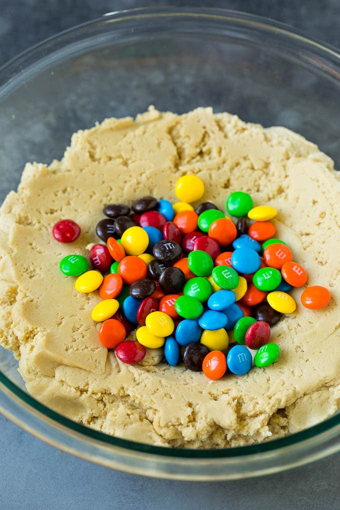 M&M Cookies Recipe #cookies #chocolate #baking #dessert #sweets #bajap A bowl of cookie dough with chocolate candies in it.