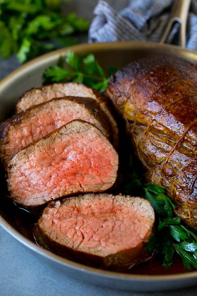 Beef Tenderloin with Garlic Butter #beef #steak #dinner #bajap A sliced beef tenderloin recipe in a pan, garnished with fresh parsley.