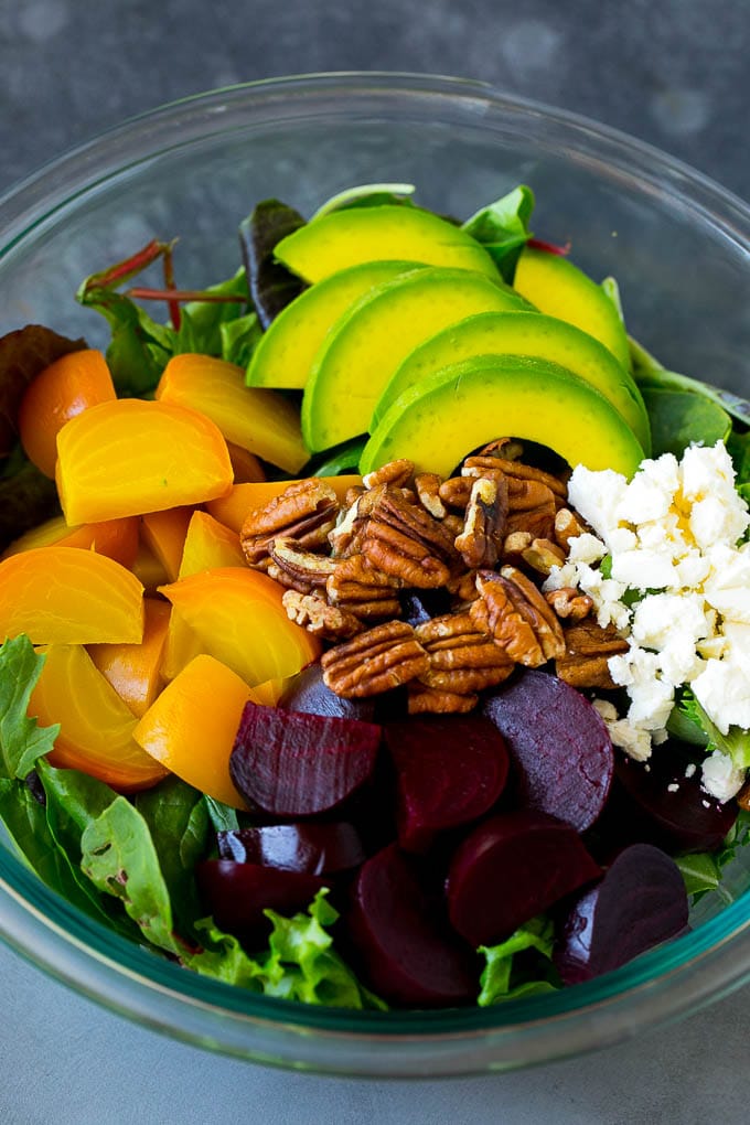 Beet Salad Recipe #beets #avocado #feta #salad #dinner #bajap Red and yellow beets, salad greens, feta cheese, avocado and pecans in a bowl.