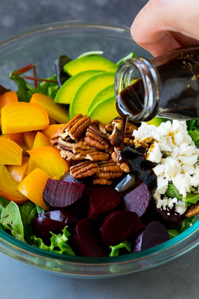 Beet Salad Recipe #beets #avocado #feta #salad #dinner #bajap Balsamic dressing being poured over beets, sliced avocado and feta cheese.