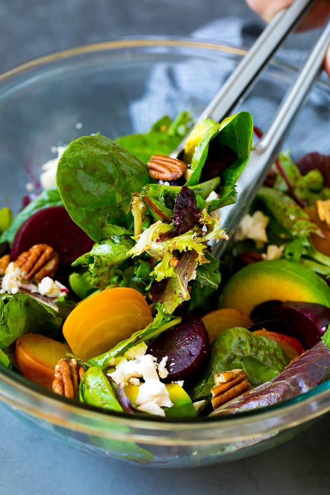 Beet Salad Recipe #beets #avocado #feta #salad #dinner #bajap Tongs serving a portion of beet salad tossed in balsamic dressing.