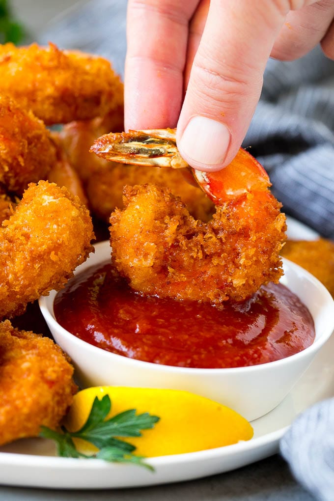 Fried Shrimp Recipe #shrimp #seafood #dinner #appetizer #bajap A hand dipping a shrimp into cocktail sauce.