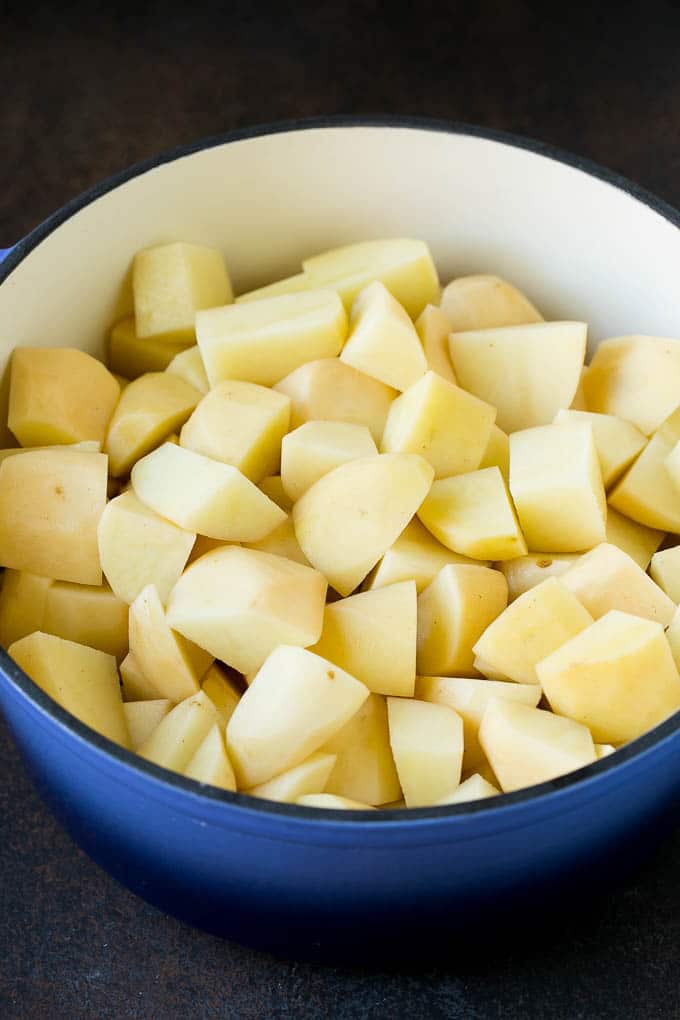 Garlic Mashed Potatoes Recipe #garlic #potatoes #mashedpotatoes #sidedish #dinner #thanksgiving #bajap Diced potatoes in a large blue pot.