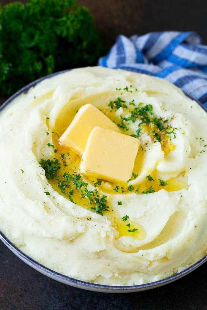 Garlic Mashed Potatoes Recipe #garlic #potatoes #mashedpotatoes #sidedish #dinner #thanksgiving #bajap Garlic mashed potatoes topped with pats of butter and parsley.