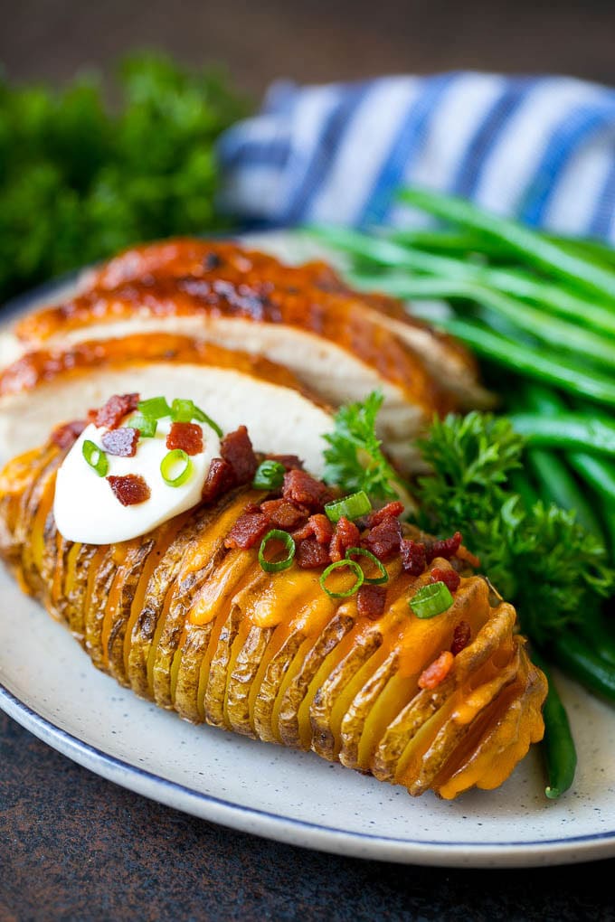 Hasselback Potatoes Recipe #potatoes #bacon #sidedish #cheese #dinner #bajap Hasselback potatoes on a plate, served with turkey and green beans.