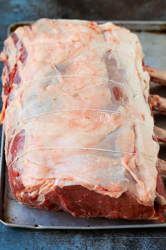 Prime Rib Recipe #primerib #beef #roast #dinner #thanksgiving #christmas #keto #lowcarb #bajap A tied standing rib roast on a sheet pan.