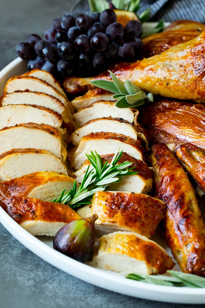 Spatchcock Turkey | Roasted Turkey | Thanksgiving Turkey #turkey #thanksgiving #dinner #fall #christmas #bajap Sliced spatchcock turkey on a serving platter garnished with herbs.