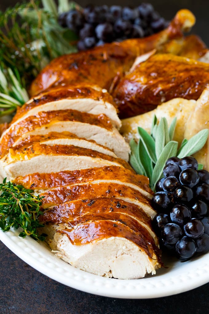 Thanksgiving Turkey Recipe | Roasted Turkey #turkey #thanksgiving #fall #dinner #bajap Sliced Thanksgiving turkey on a serving platter with fresh herbs.