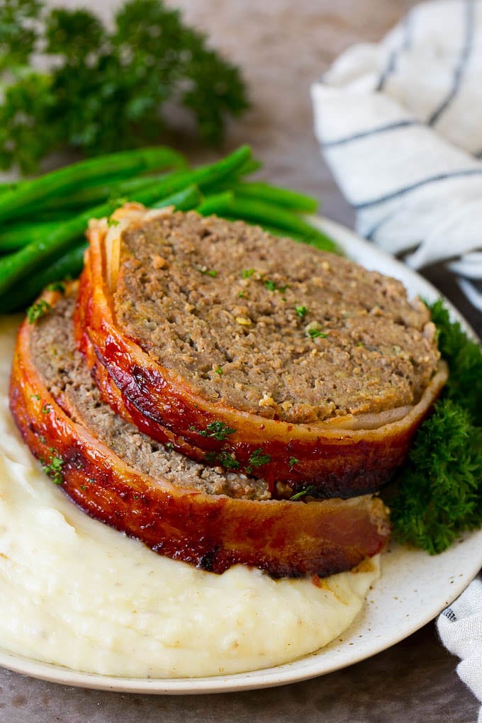 Bacon Wrapped Meatloaf Recipe | Beef Meatloaf #meatloaf #beef #groundbeef #bacon #dinner #bajap Slices of bacon wrapped meatloaf served over mashed potatoes with green beans.