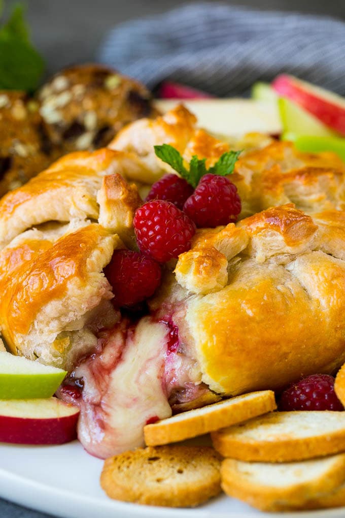 Baked Brie Recipe | Pastry Wrapped Brie #brie #cheese #appetizer #pecans #raspberries #bajap Baked brie cut open with cheese spilling out.