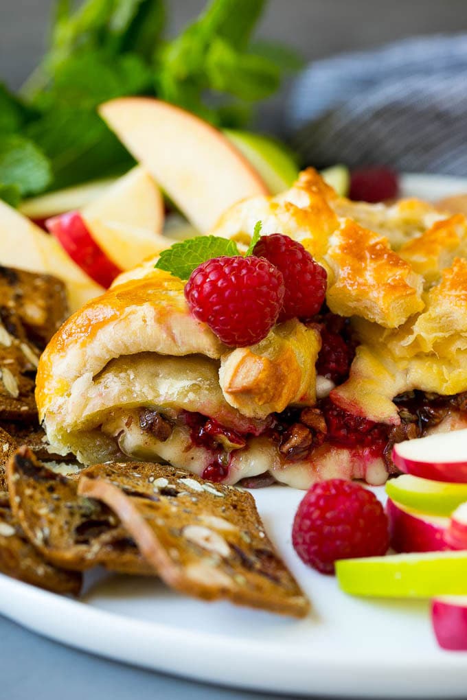 Baked Brie Recipe | Pastry Wrapped Brie #brie #cheese #appetizer #pecans #raspberries #bajap A cross section of baked brie filled with raspberries and pecans.