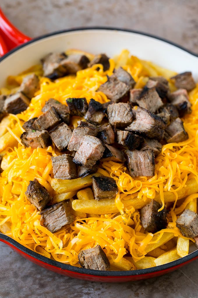 Carne Asada Fries Recipe | Steak Fries #fries #frenchfries #steak #salsa #avocado #cheese #dinner #appetizer #bajap French fries topped with shredded cheese and diced steak.