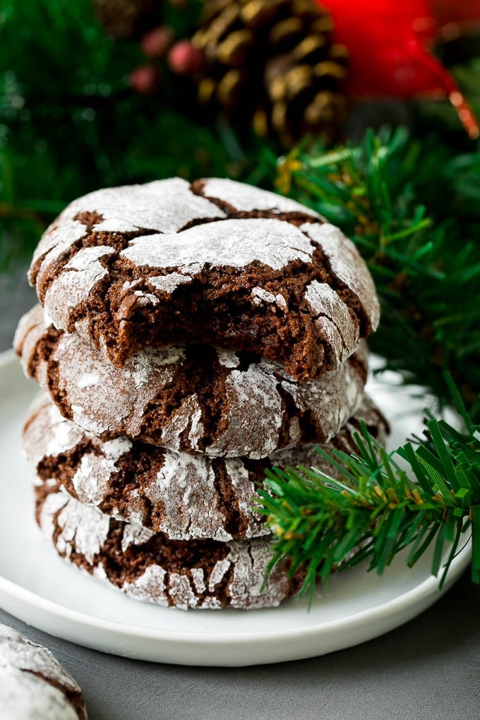 Chocolate Crinkle Cookies Recipe #cookies #chocolate #christmas #dessert #baking #bajap A stack of chocolate crinkle cookies with a bite taken out of one.