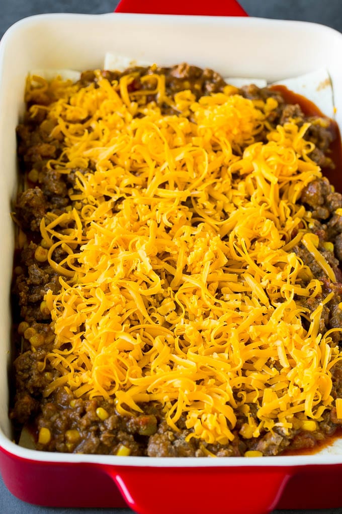 Mexican Lasagna Recipe | Mexican Casserole #mexican #lasagna #groundbeef #beans #dinner #cheese #bajap Layers of tortillas, ground beef and shredded cheese in a baking dish.