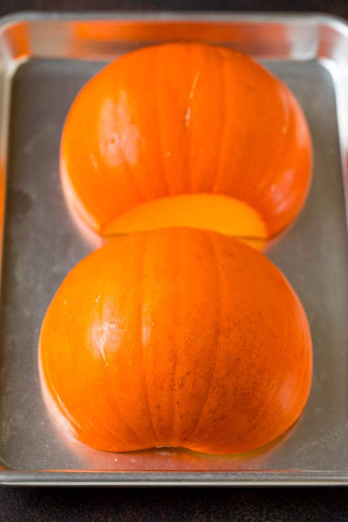 Pumpkin Puree Recipe #pumpkin #baking #fall #thanksgiving #bajap A pumpkin cut in half on a sheet pan.