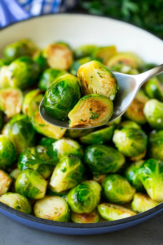 Sauteed Brussels Sprouts Recipe | Brussels Sprouts Side Dish #brusselssprouts #sprouts #veggies #sidedish #garlic #vegetarian #dinner #bajap A spoon holding up a serving of cooked brussels sprouts.