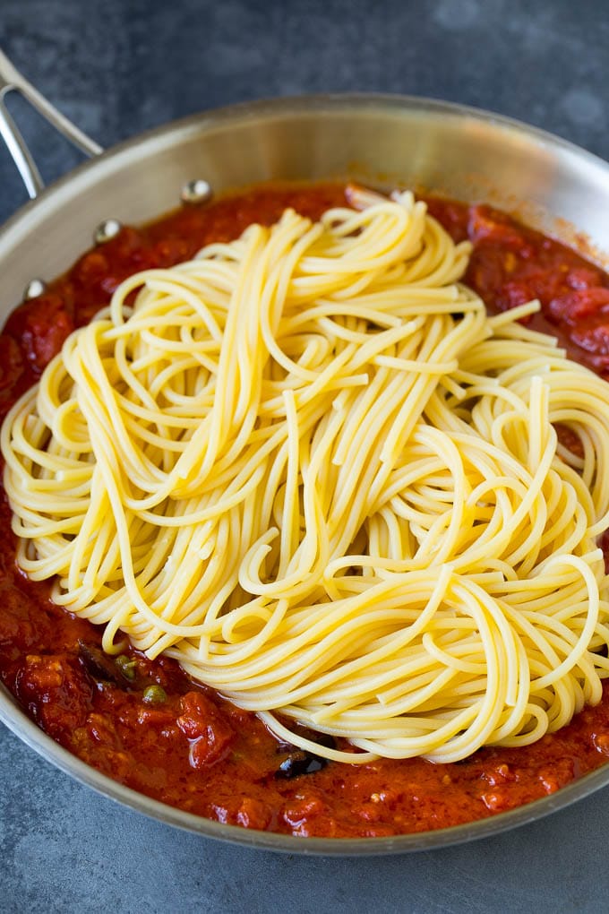 Pasta Puttanesca Recipe #pasta #tomatoes #olives #italianfood #dinner #bajap Spaghetti in a pan of tomato sauce with olives and capers.