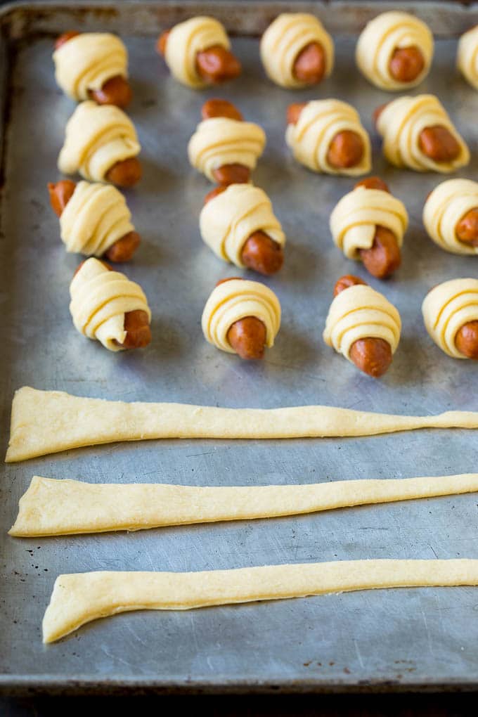 Pigs in a Blanket Recipe #hotdogs #appetizer #snack #comfortfood #bajap Strips of crescent dough on a sheet pan.