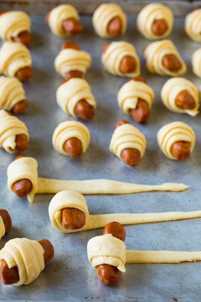 Pigs in a Blanket Recipe #hotdogs #appetizer #snack #comfortfood #bajap Hot dogs being rolled up in dough.