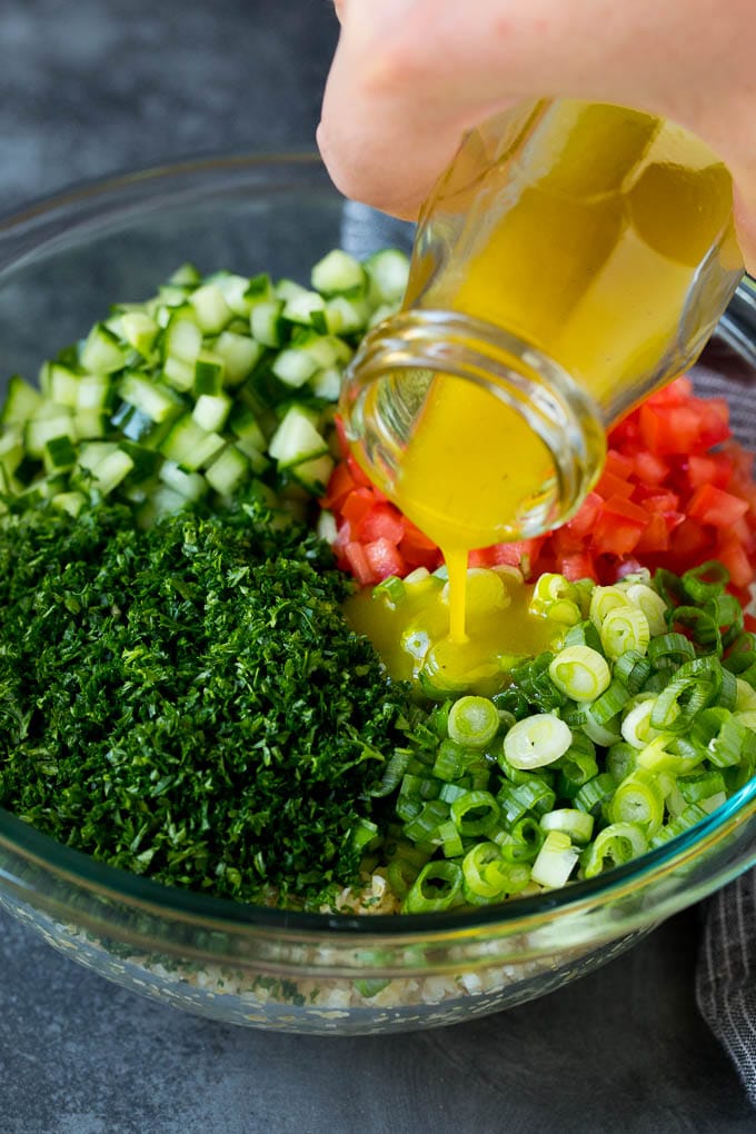 Tabbouleh Salad | Tabouli #salad #wheat #tomatoes #cucumber #healthy #sidedish #dinner #bajap Dressing being poured into a bowl of bulgur wheat salad.