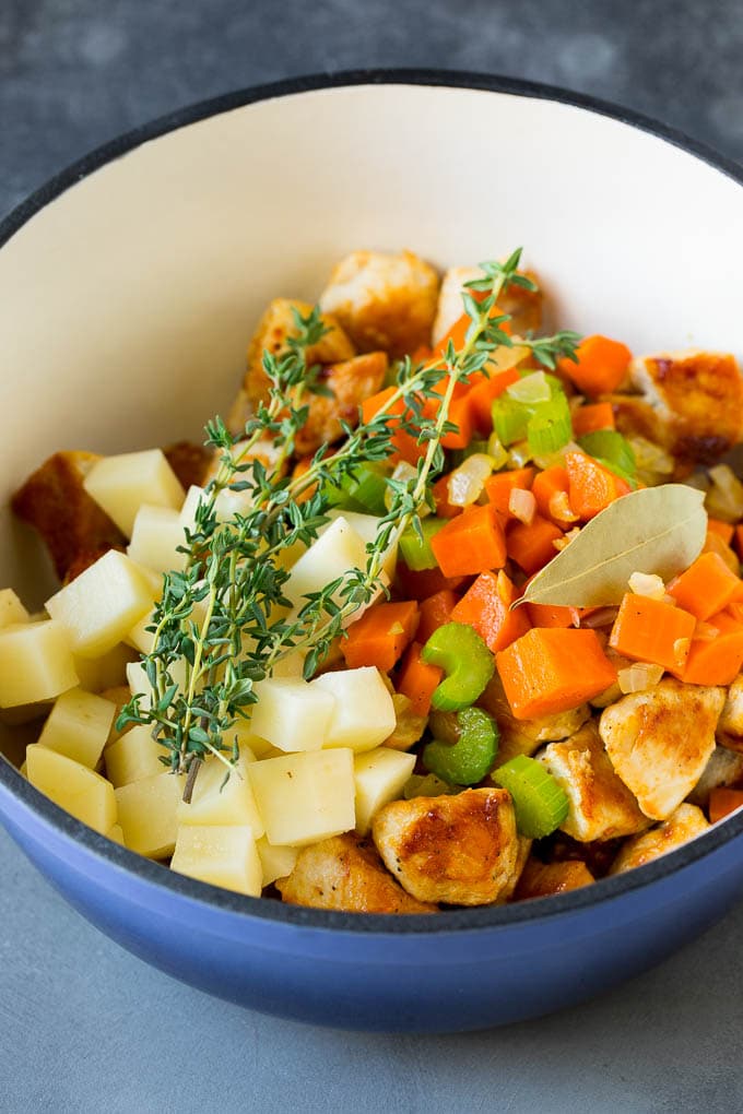 Chicken Pot Pie Soup Recipe | Chicken Soup #soup #chicken #dinner #comfortfood #bajap Ingredients such as vegetables, potatoes and herbs in a pot.
