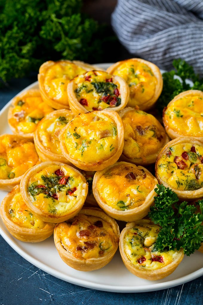 Mini Quiche Recipe #eggs #breakfast #brunch #appetizer #bajap A plate of mini quiche filled with meats, vegetables and cheeses.