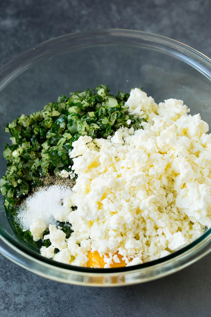 Spanakopita Recipe #appetizer #snack #spinach #cheese #bajap Spinach, onions, herbs and feta cheese in a bowl.