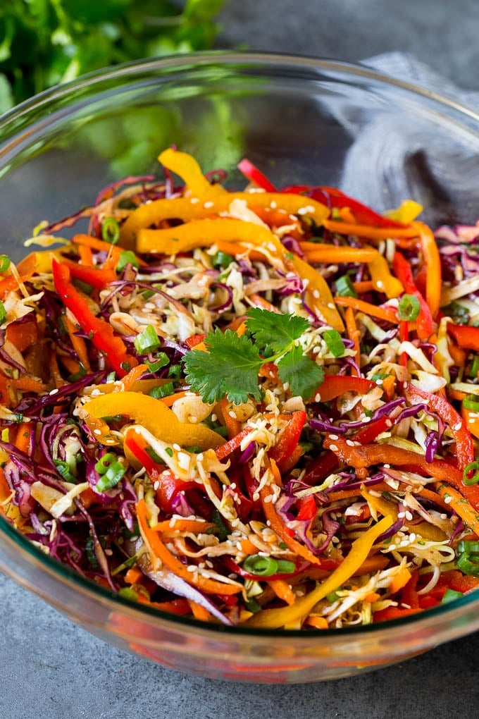 Asian Slaw Recipe #salad #slaw #sidedish #bajap A bowl of Asian slaw garnished with sesame seeds and herbs.